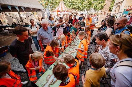 Je ziet kinderen aan in oranje hesjes werken aan een wildwaterbaan 
