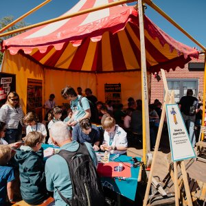 Kinderen zitten aan lange tafels en doen een spel